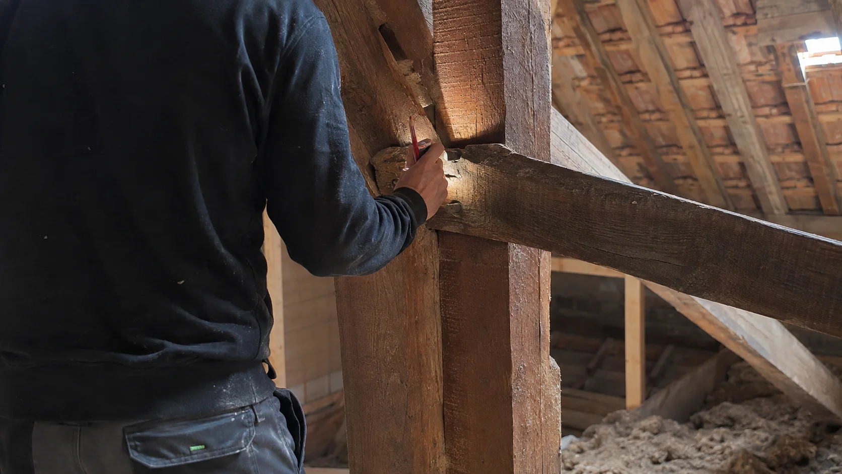 Artisan inspectant une charpente traditionnelle